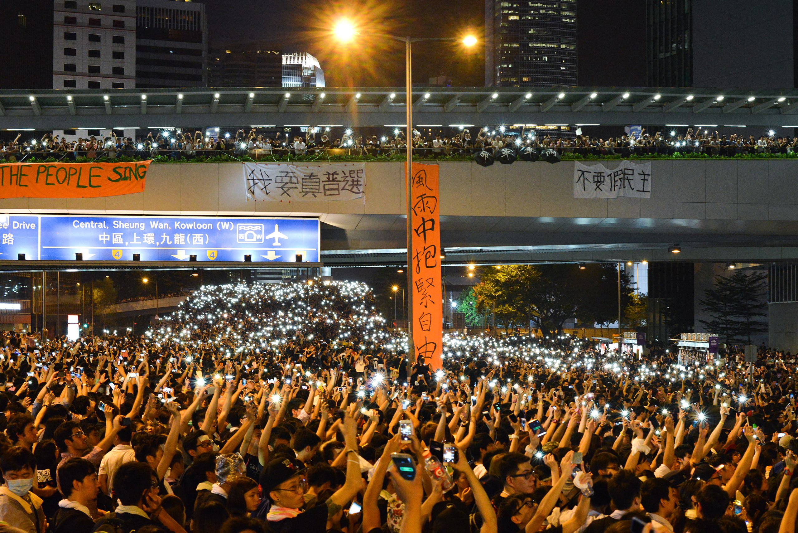 警方采取武力驱散后，数以万计的市民占领金钟干道，并亮起手机灯光
